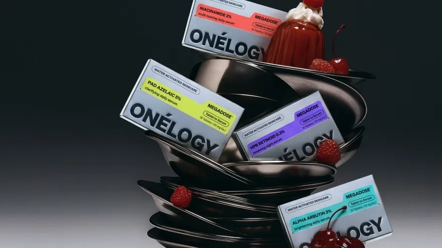 Four skincare boxes on a stack of metal plates, with cherries and raspberries against a dark background.