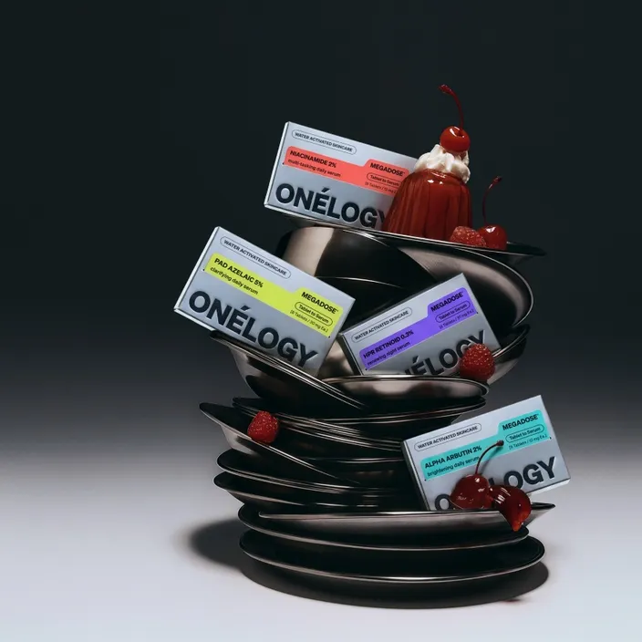 Four skincare boxes on a stack of metal plates, with cherries and raspberries against a dark background.