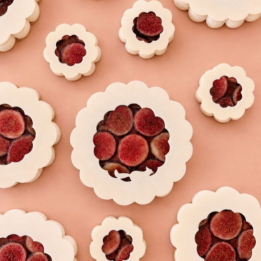 Pâtisseries festonnées garnies de figues, vues du dessus sur un fond rose.